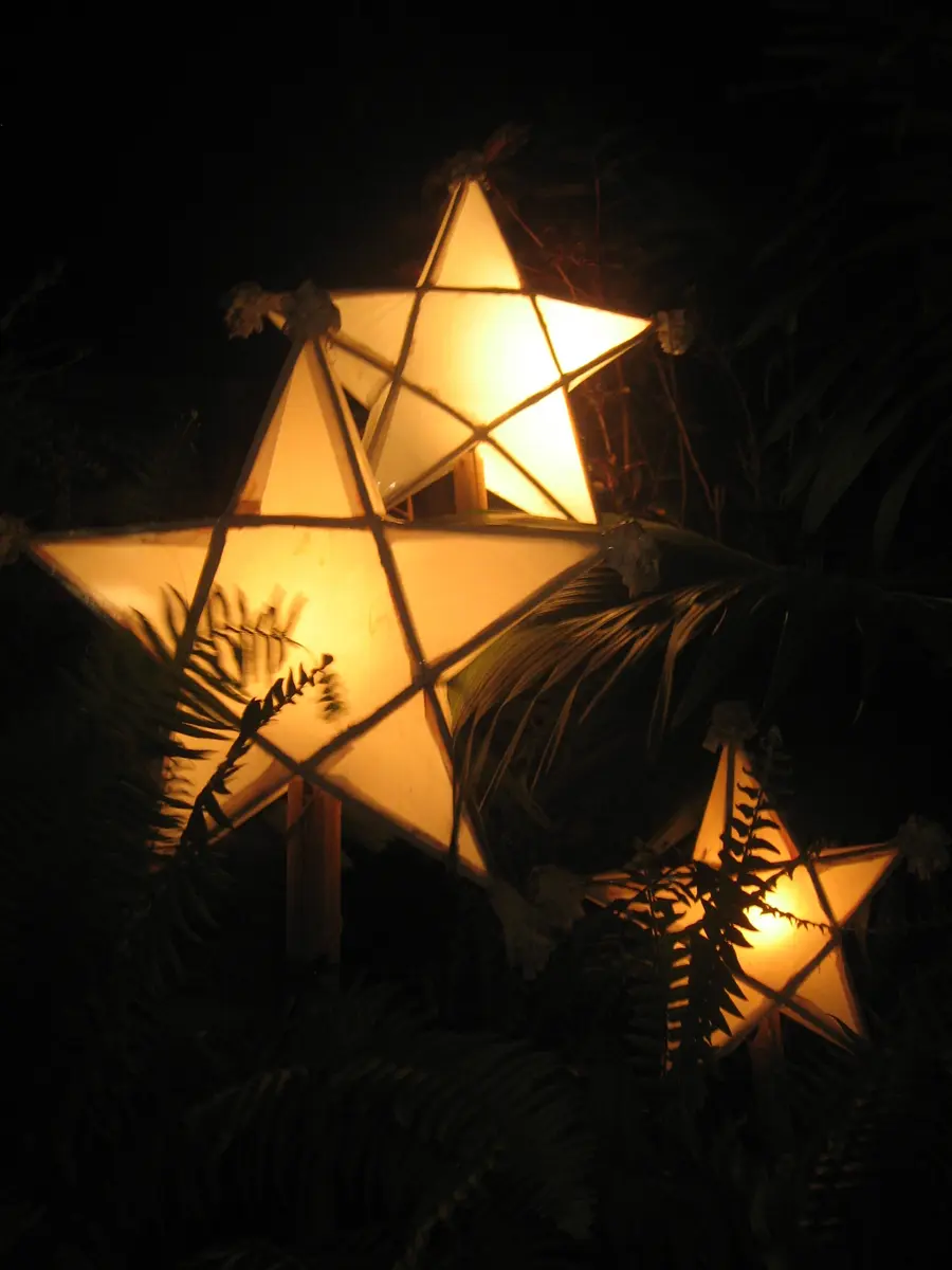 Three traditional star-shaped parol lanterns glowing at night