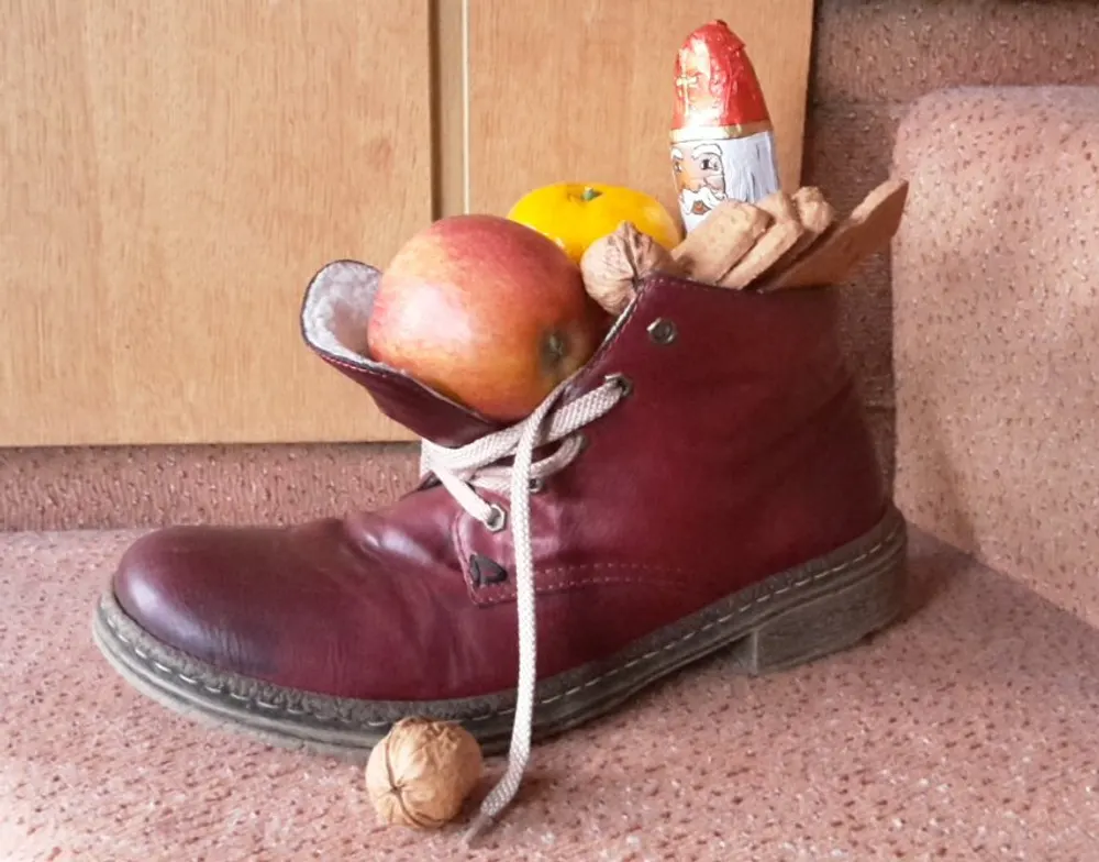 A leather boot filled with an apple, a mandarin, walnuts, spiced cookies and a chocolate St Nicholas