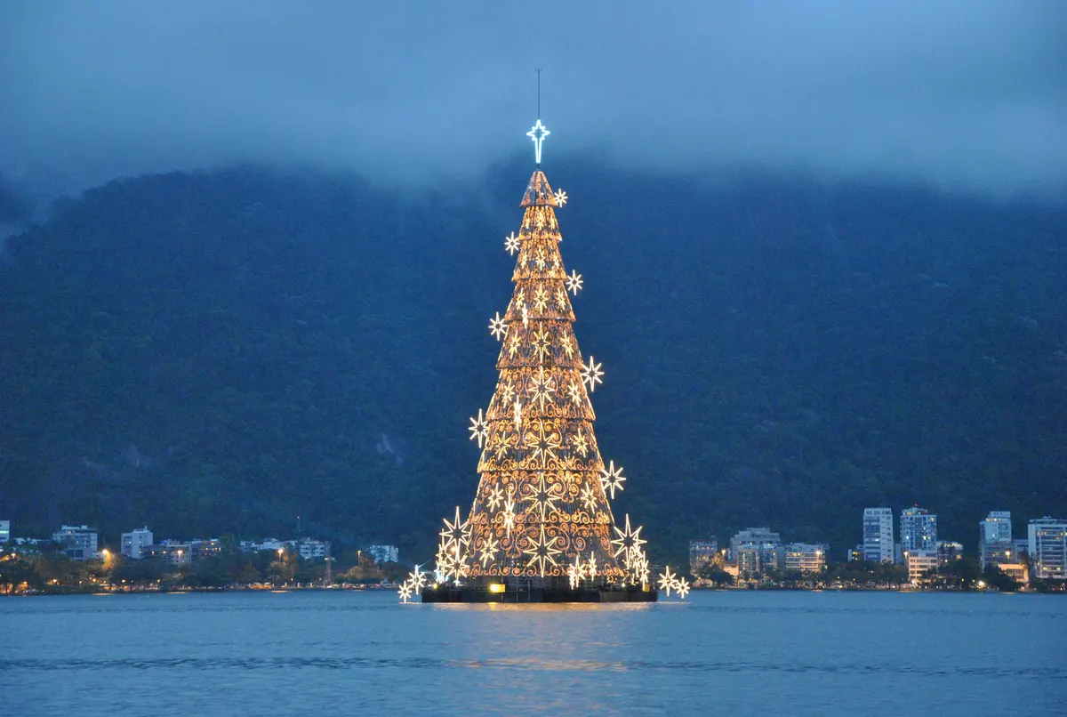 Árvore de Natal flutuante da Lagoa Rodrigo de Freitas ao anoitecer, com o morro ao fundo