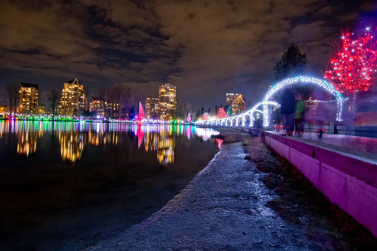 Lights at Lafarge Lake in Coquitlam: illuminated walkway and lights reflected on the water with the city skyline