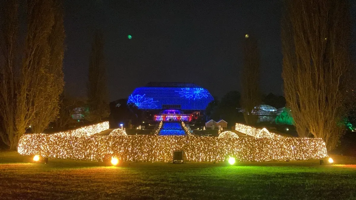 Christmas Garden Berlin im Botanischen Garten mit blau beleuchtetem Tropenhaus und Lichtermeer auf der Wiese