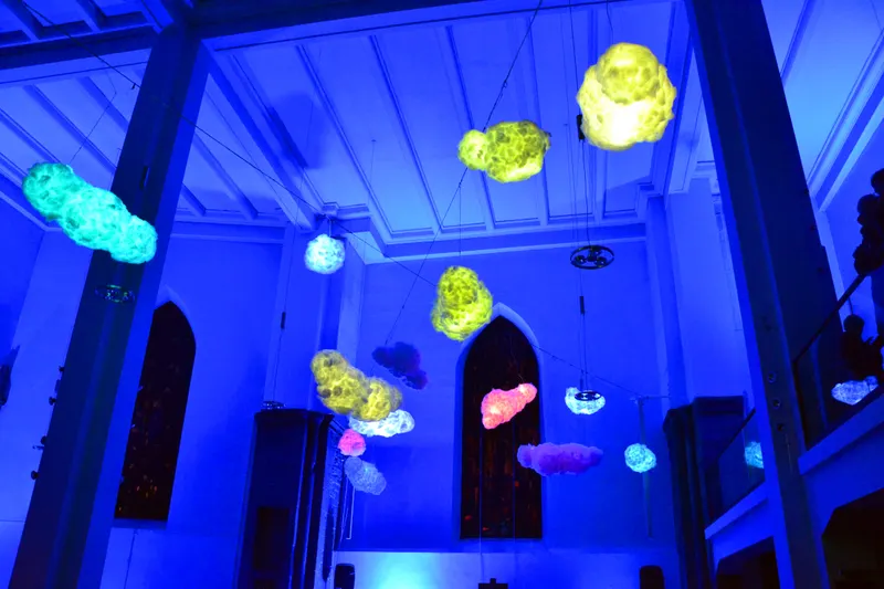 Bunte Lichtwolken im blau beleuchteten Kirchenraum der Marktkirche Essen