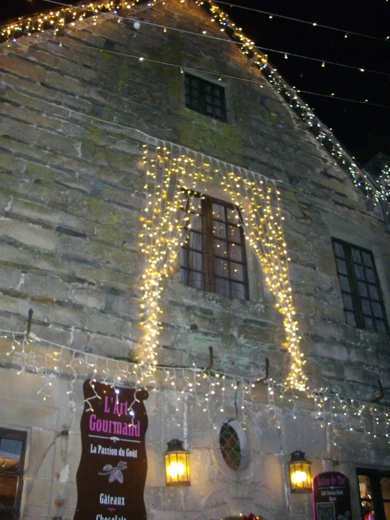 Mur de pierre aux fenêtres drapées de rideaux lumineux à Rochefort-en-Terre