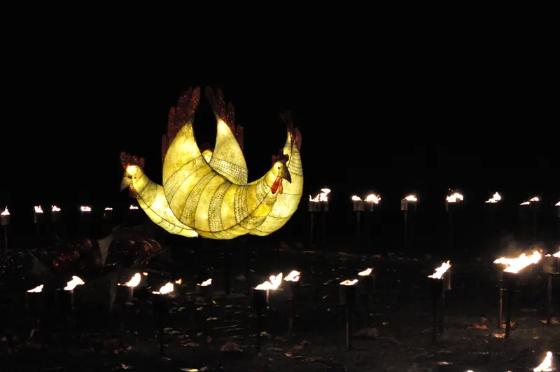 Glowing lantern figure and flame torches at Christmas at Kew