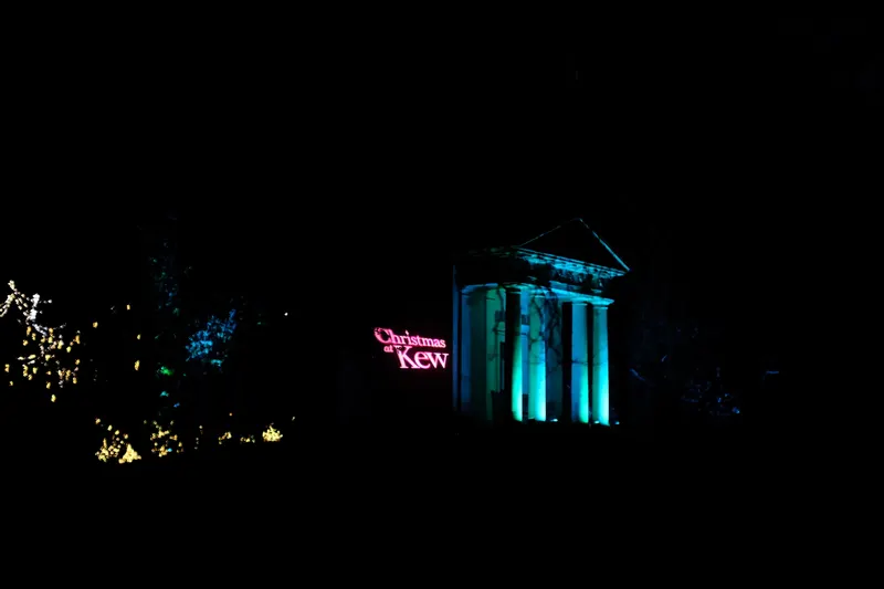 Christmas at Kew sign glowing beside a lit temple in the gardens
