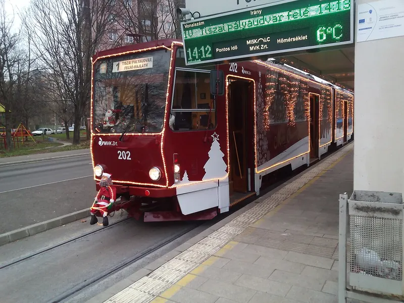 Bordó karácsonyi díszítésű villamos a miskolci megállóban