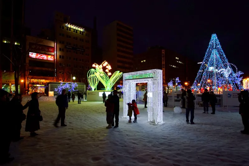雪の夜の大通公園、光のゲートとイルミネーションを楽しむ人々