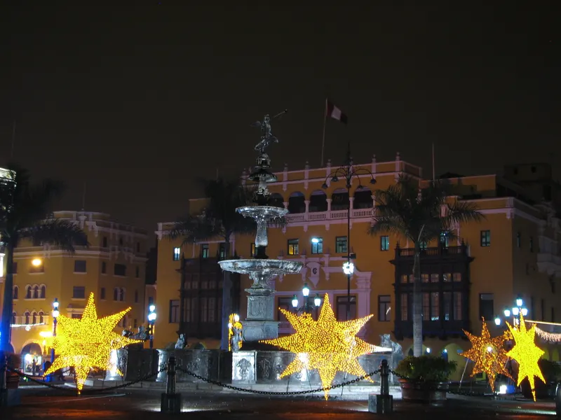 Estrellas doradas iluminadas junto a la pila de la Plaza Mayor de Lima en Navidad