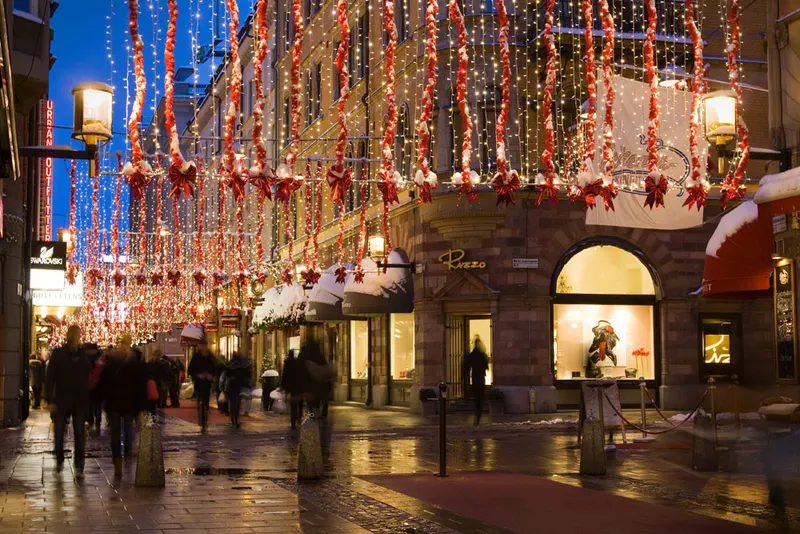 Biblioteksgatan i Stockholm med hängande julbelysning en snöig kväll