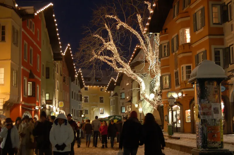 Beleuchteter Baum und Passanten in der Kitzbüheler Altstadt im Advent