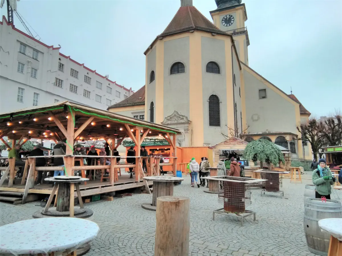 Wintermarkt am Pfarrplatz in Linz mit Pfarrkirche und überdachten Stehtischen