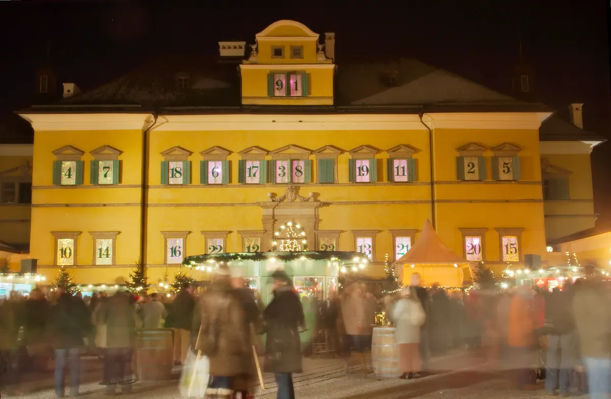 Schloss Hellbrunn mit Adventkalender-Fenstern und Besuchern auf dem Adventzauber