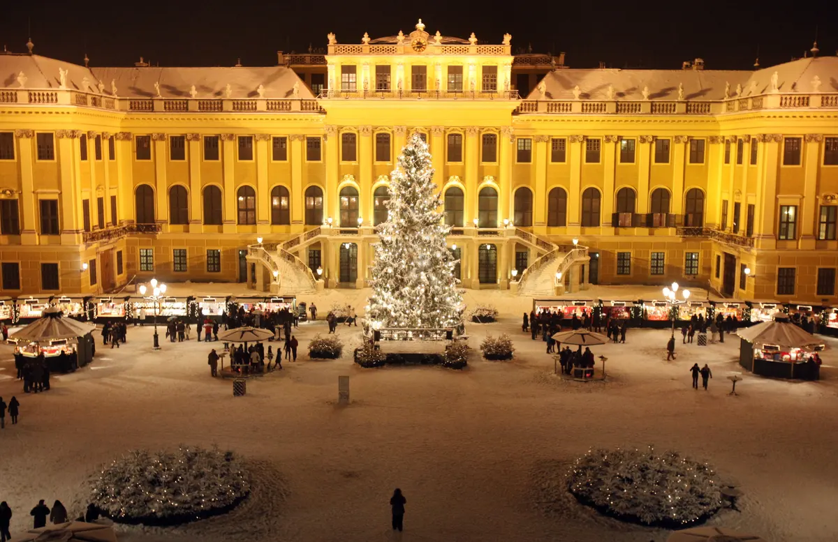 Schloss Schönbrunn mit großem Weihnachtsbaum und Marktständen im Schnee