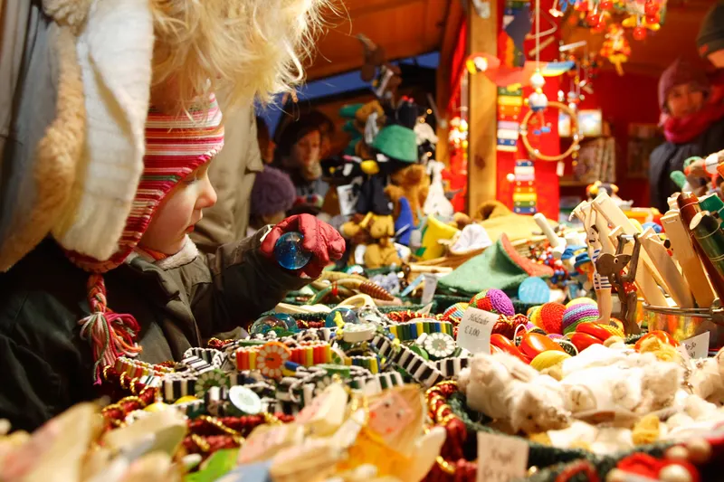 Kind schaut sich Spielzeug und Christbaumschmuck am Weihnachtsmarkt Schönbrunn an
