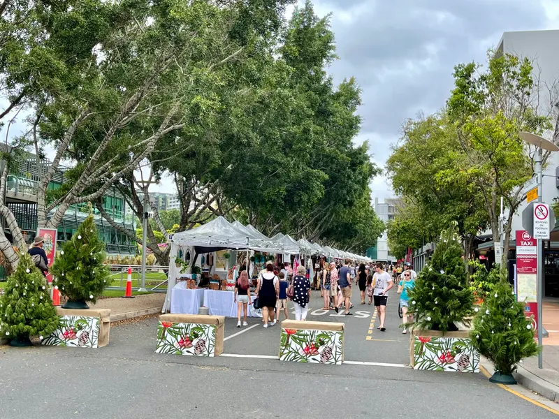 Rows of white market tents along a tree-lined street in South Brisbane at Christmas