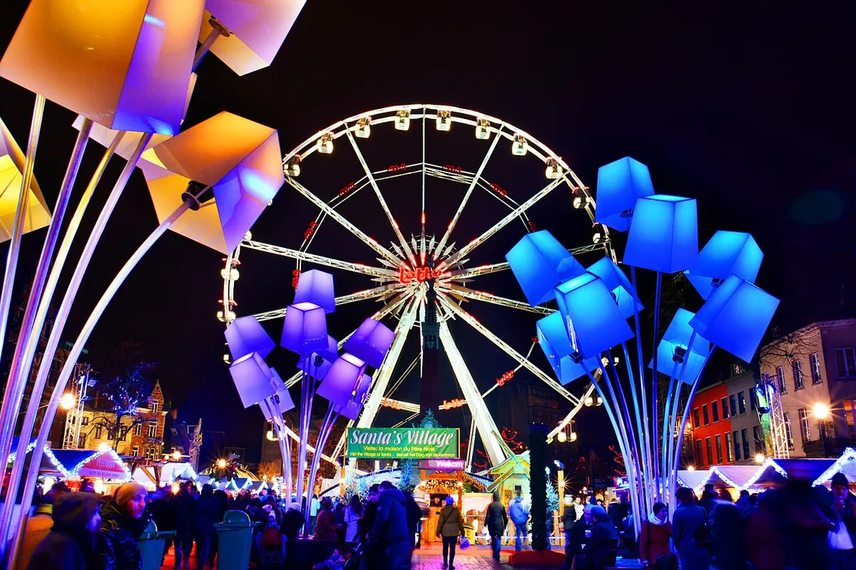 Verlicht reuzenrad en kerstdorp op Winterpret in Brussel bij avond