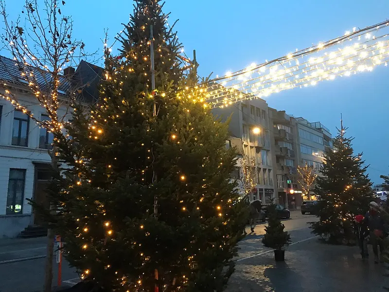 Kermisattracties voor de kerk tijdens Winterpret in Deinze