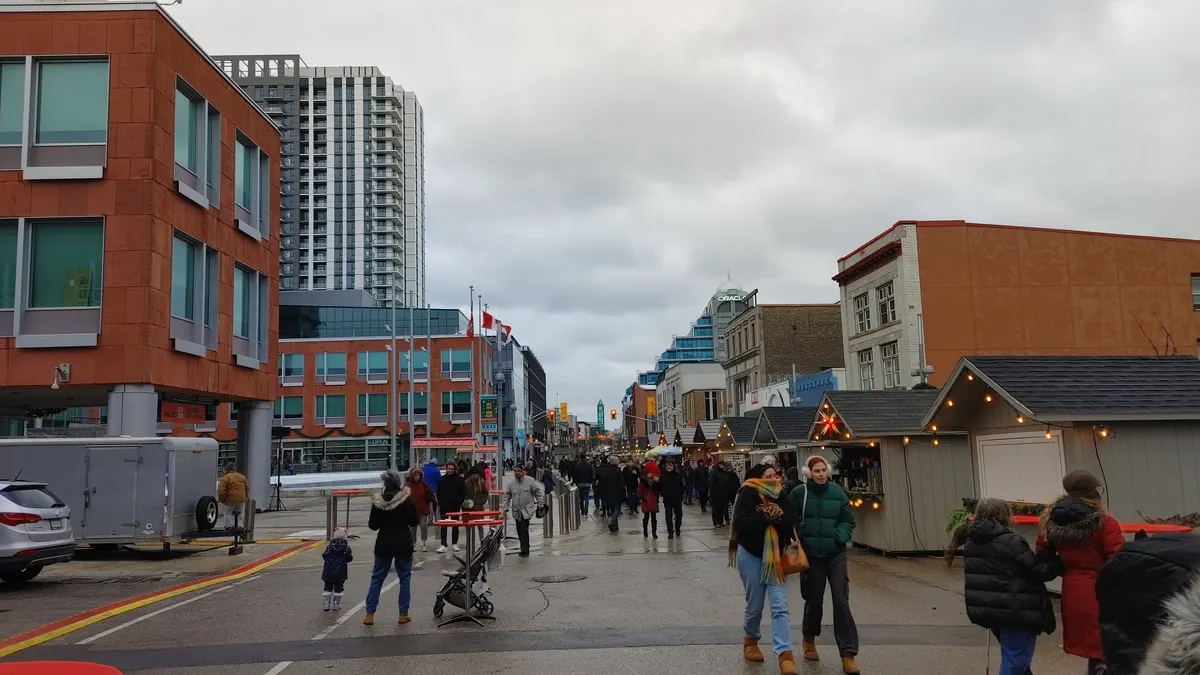 Visitors walking between wooden chalets at the Christkindl Market in downtown Kitchener, Ontario