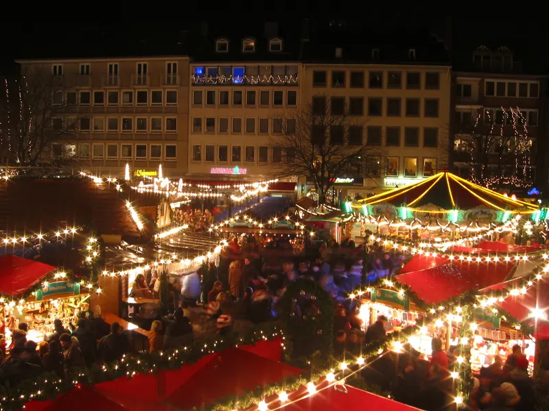 Aachener Weihnachtsmarkt bei Nacht mit bunten Lichterketten