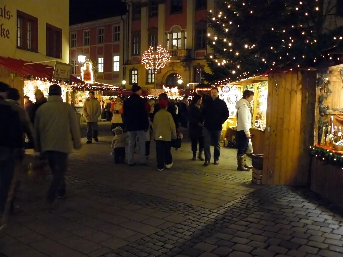 Besucher zwischen Marktständen auf dem Ansbacher Weihnachtsmarkt am Abend