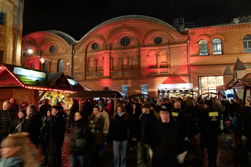 Rot beleuchtete Backsteingebäude der Kulturbrauerei mit Marktbuden