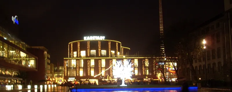 Lichterbaum und beleuchtetes Kaufhaus am Weihnachtsmarkt in Duisburg