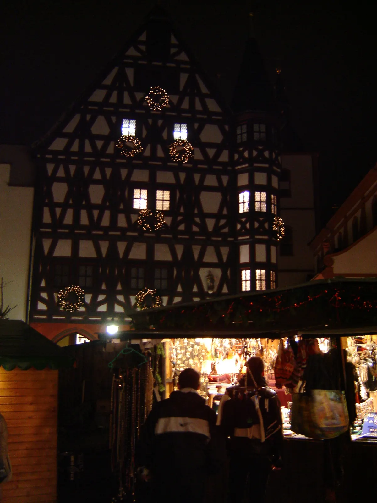 Fachwerkhaus mit Kränzen über einem Marktstand auf dem Fuldaer Weihnachtsmarkt bei Nacht