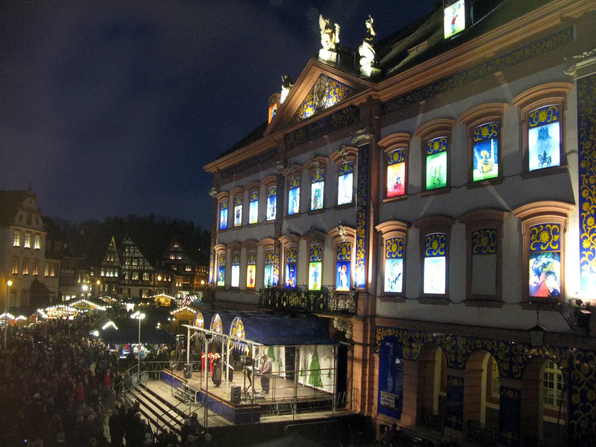 Gengenbacher Rathaus als Adventskalender bei Nacht, davor der Adventsmarkt