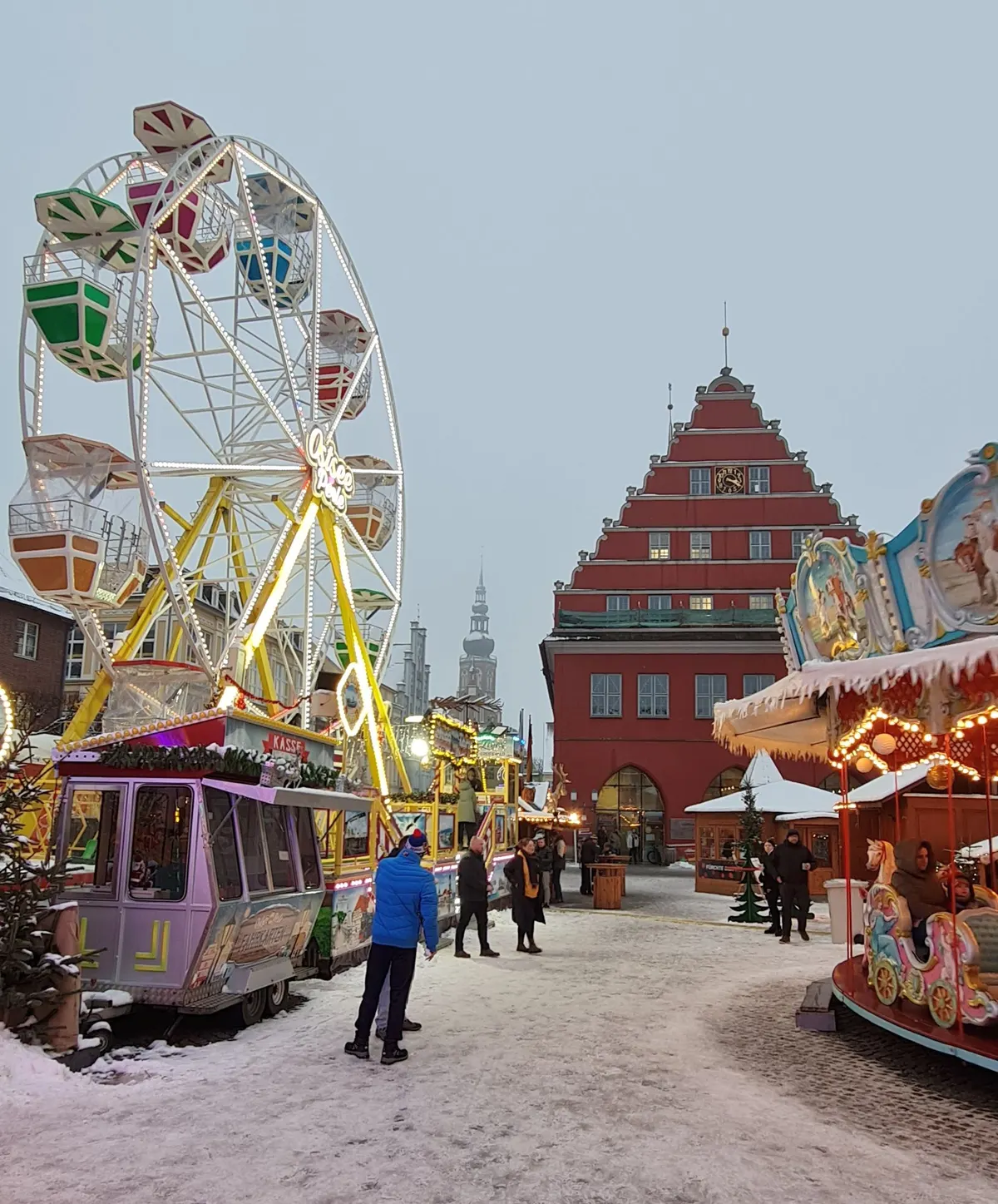 Verschneiter Greifswalder Weihnachtsmarkt mit Riesenrad vor dem Rathaus
