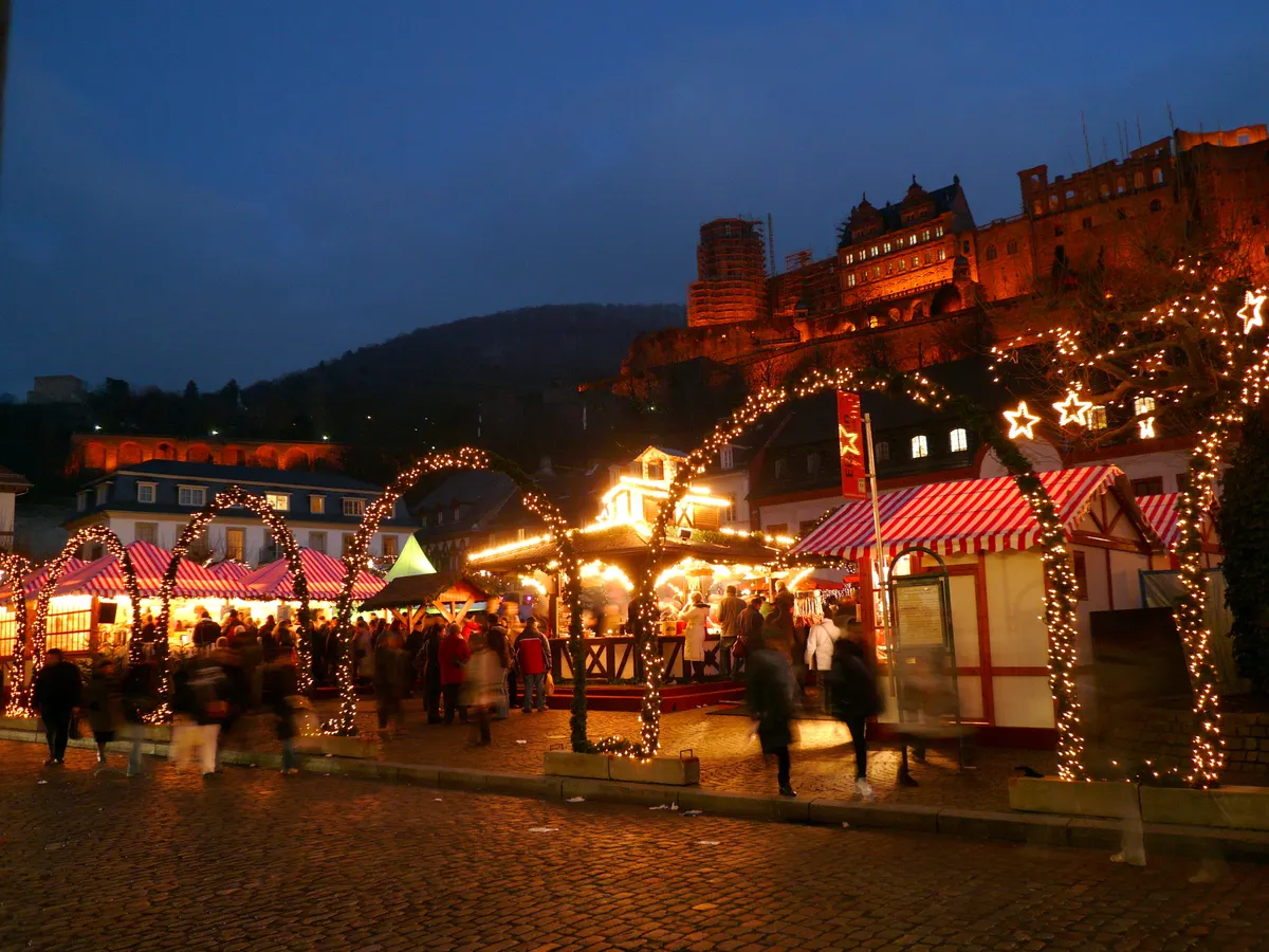 Heidelberger Weihnachtsmarkt mit angestrahltem Schloss im Hintergrund