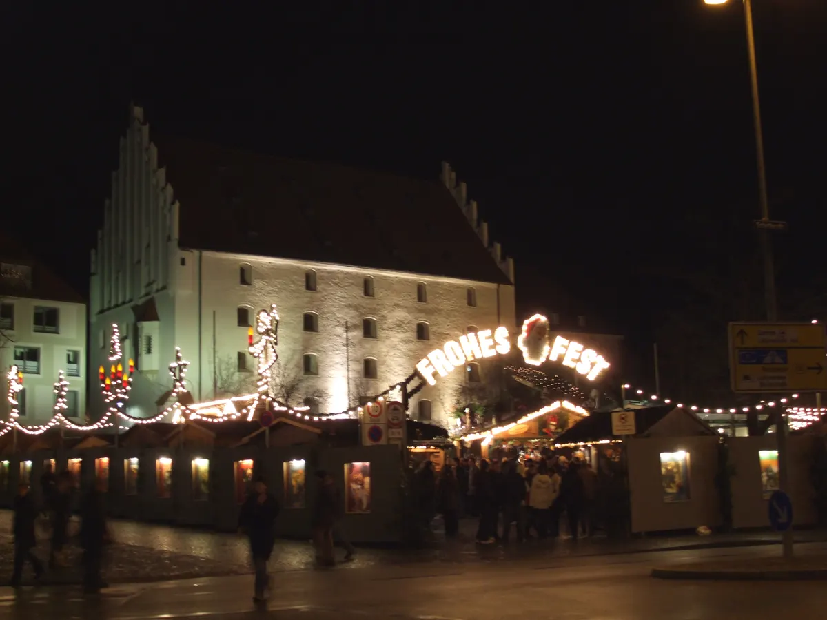 Ingolstädter Christkindlmarkt bei Nacht mit beleuchtetem Eingangsbogen Frohes Fest