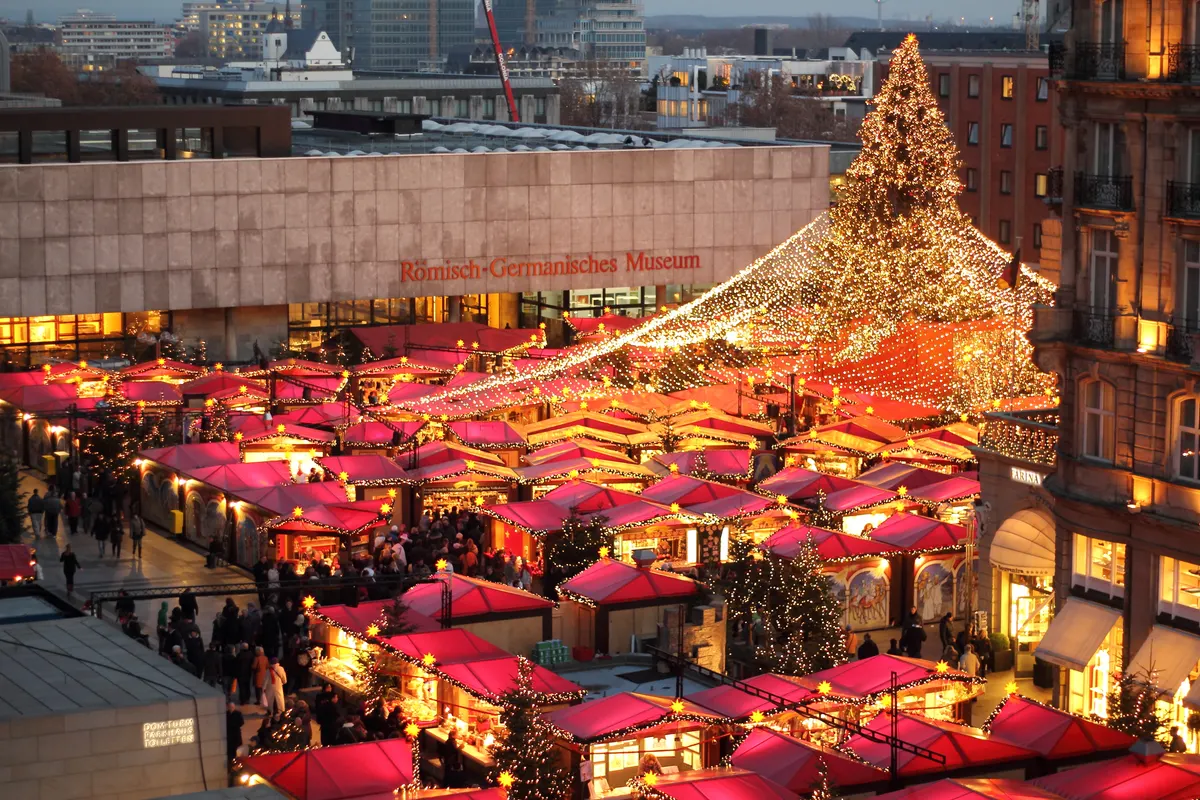 Weihnachtsmarkt am Kölner Dom mit roten Buden und leuchtendem Lichterhimmel von oben