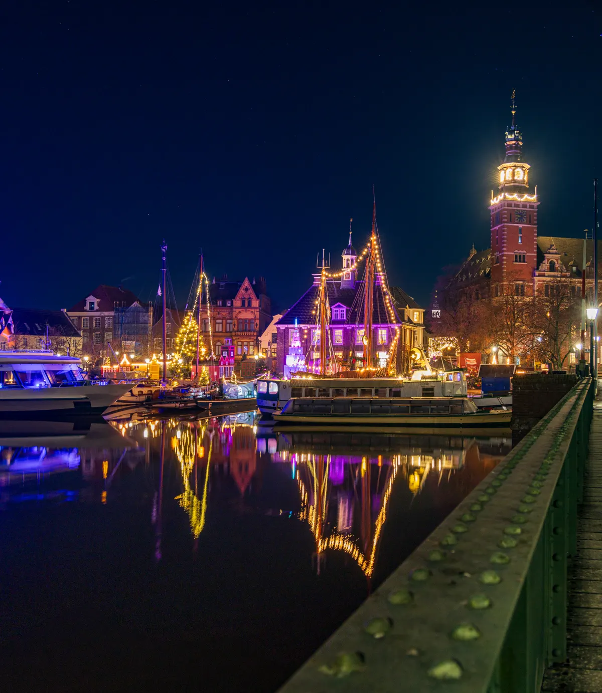 Beleuchtete Schiffe und Rathausturm im Hafen von Leer zur Weihnachtszeit