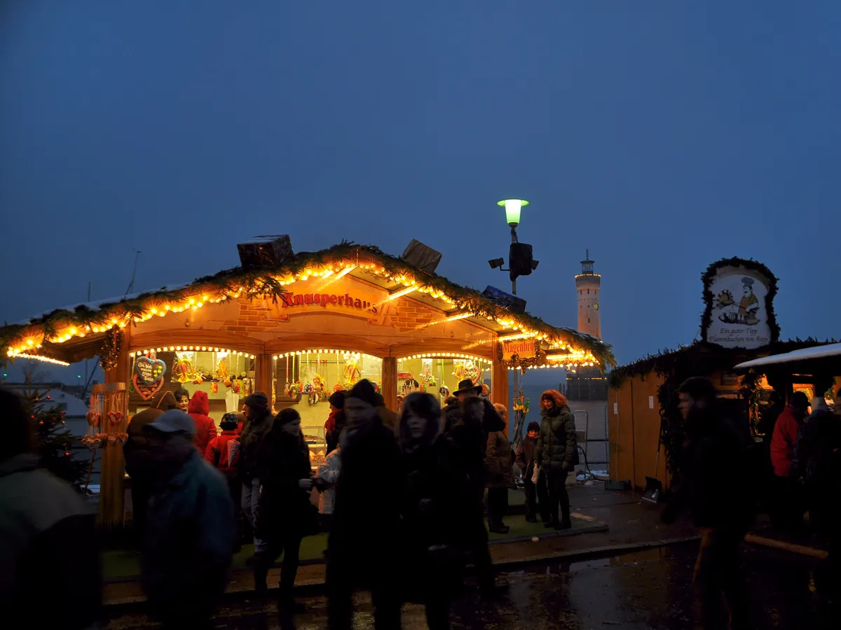 Hütte der Lindauer Hafenweihnacht am Abend vor dem Leuchtturm