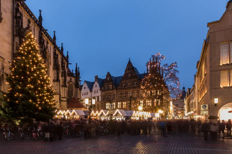 Weihnachtsmarkt am Lambertikirchplatz in Münster zur blauen Stunde mit beleuchtetem Tannenbaum