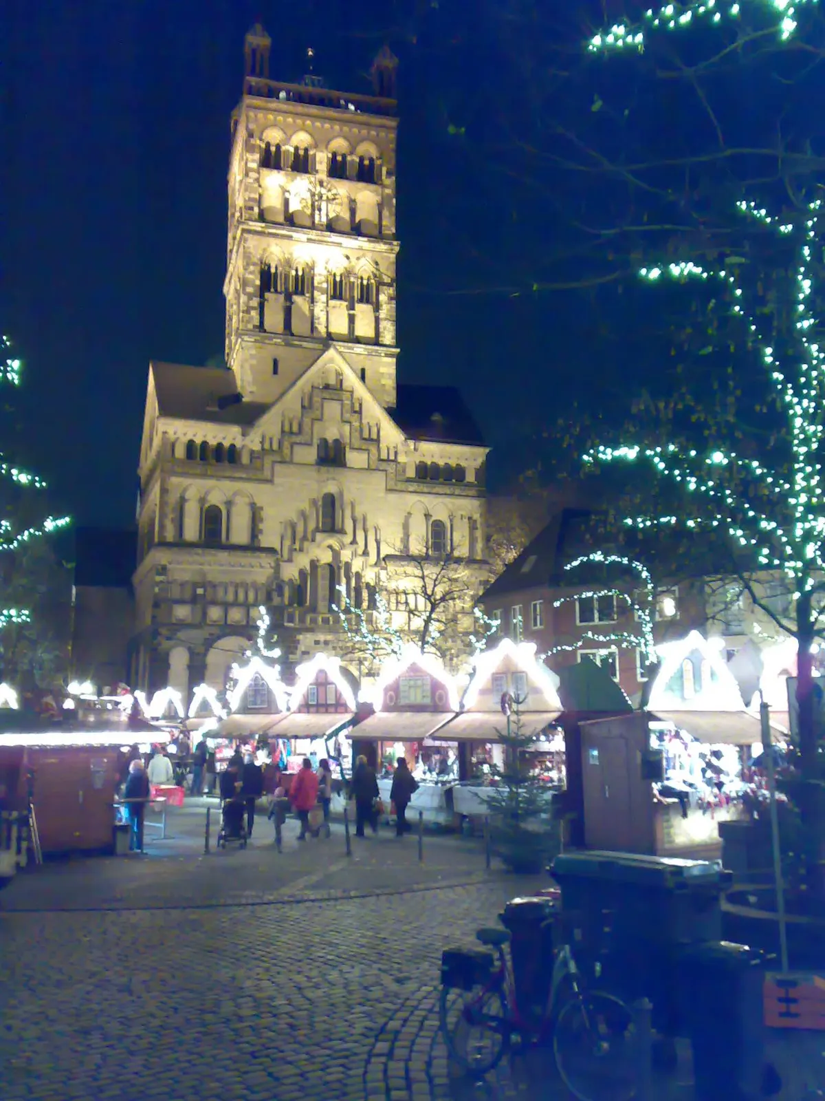 Neusser Weihnachtsmarkt am Quirinus-Münster bei Nacht mit beleuchteten Bäumen und Buden