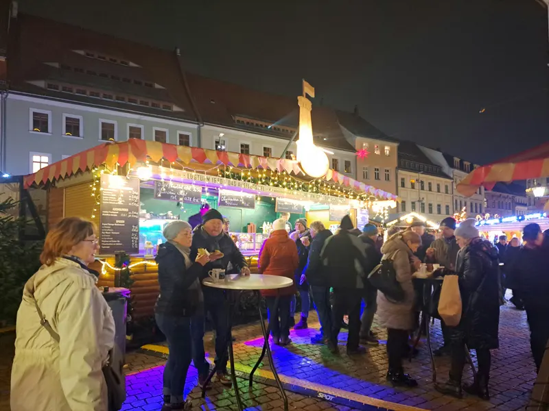 Glühweinstand mit Besuchern auf dem Canalettomarkt in Pirna am Abend
