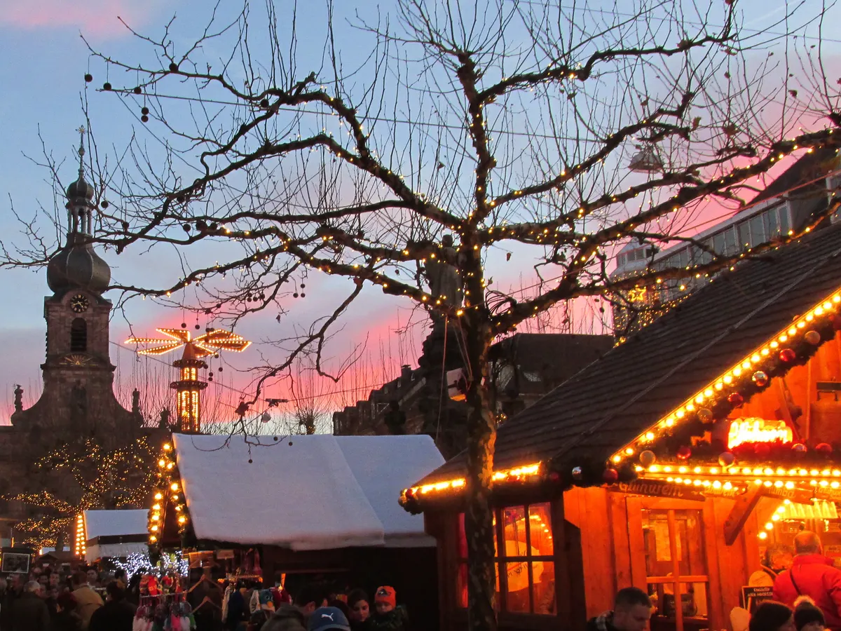 Rastatter Weihnachtsmarkt im Abendrot mit Stadtkirche und beleuchteten Hütten