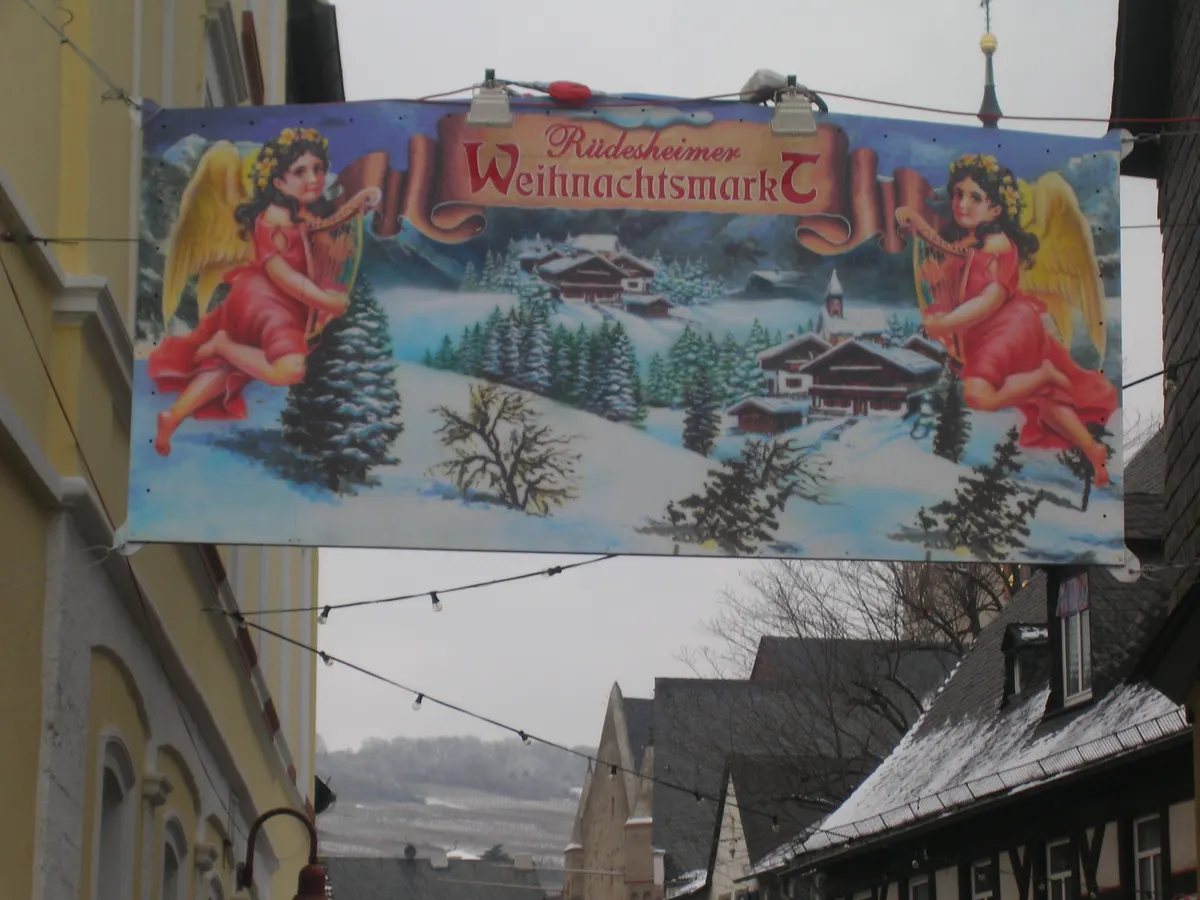 Schild des Rüdesheimer Weihnachtsmarkts mit Engeln und Winterlandschaft
