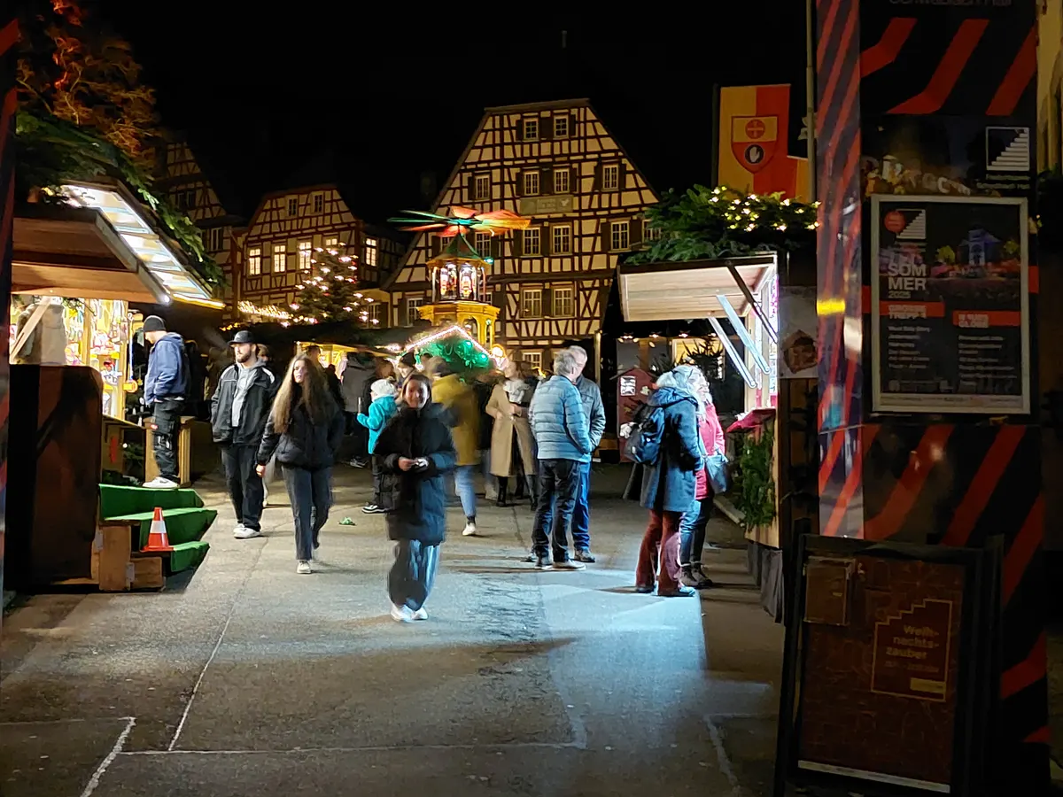 Besucher auf dem Schwäbisch Haller Weihnachtsmarkt zwischen Fachwerkhäusern am Abend