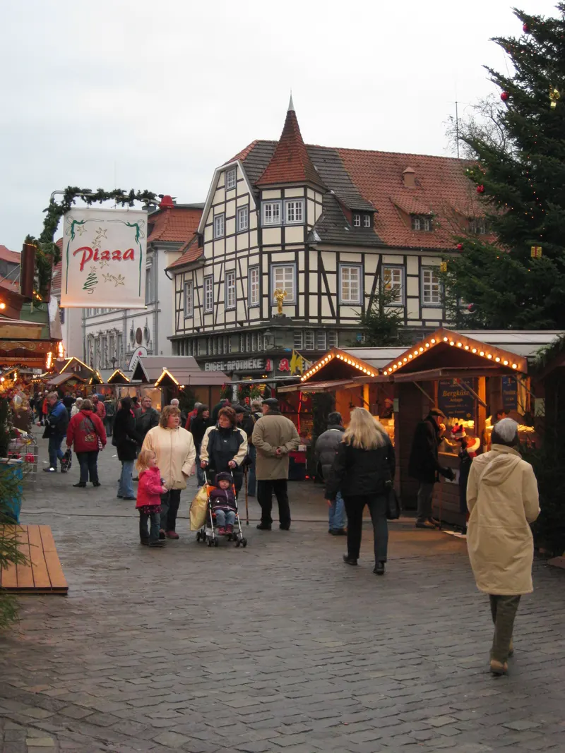 Besucher zwischen Holzhütten vor Fachwerkhäusern auf dem Soester Weihnachtsmarkt