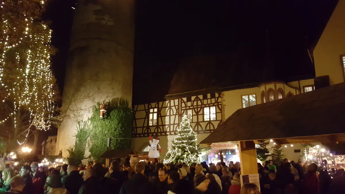 Weihnachtsmarkt Tauberbischofsheim am Kurmainzischen Schloss mit Menschenmenge und Fachwerkhaus bei Nacht