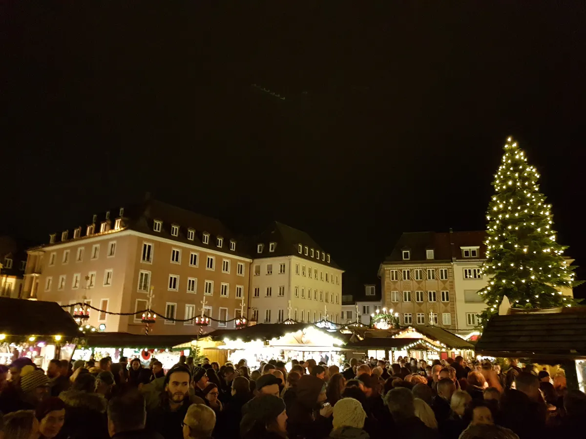Würzburger Weihnachtsmarkt bei Nacht mit großem beleuchteten Weihnachtsbaum und Menschenmenge