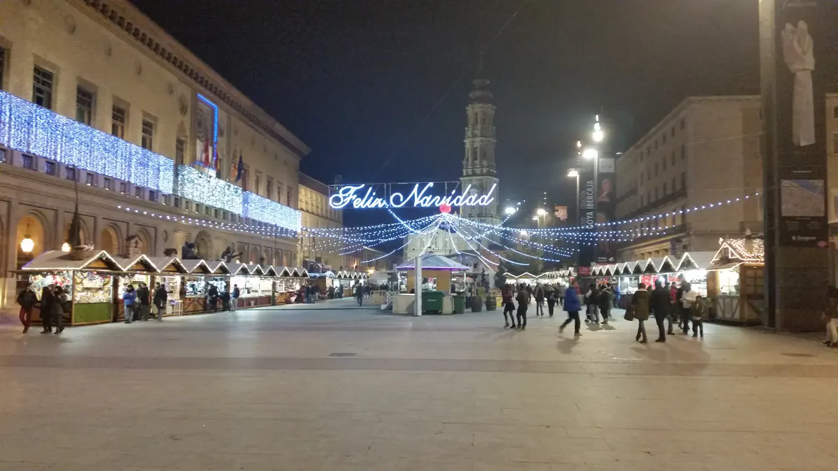 Casetas del mercadillo de Navidad en la Plaza del Pilar de Zaragoza con la torre de la basílica al fondo