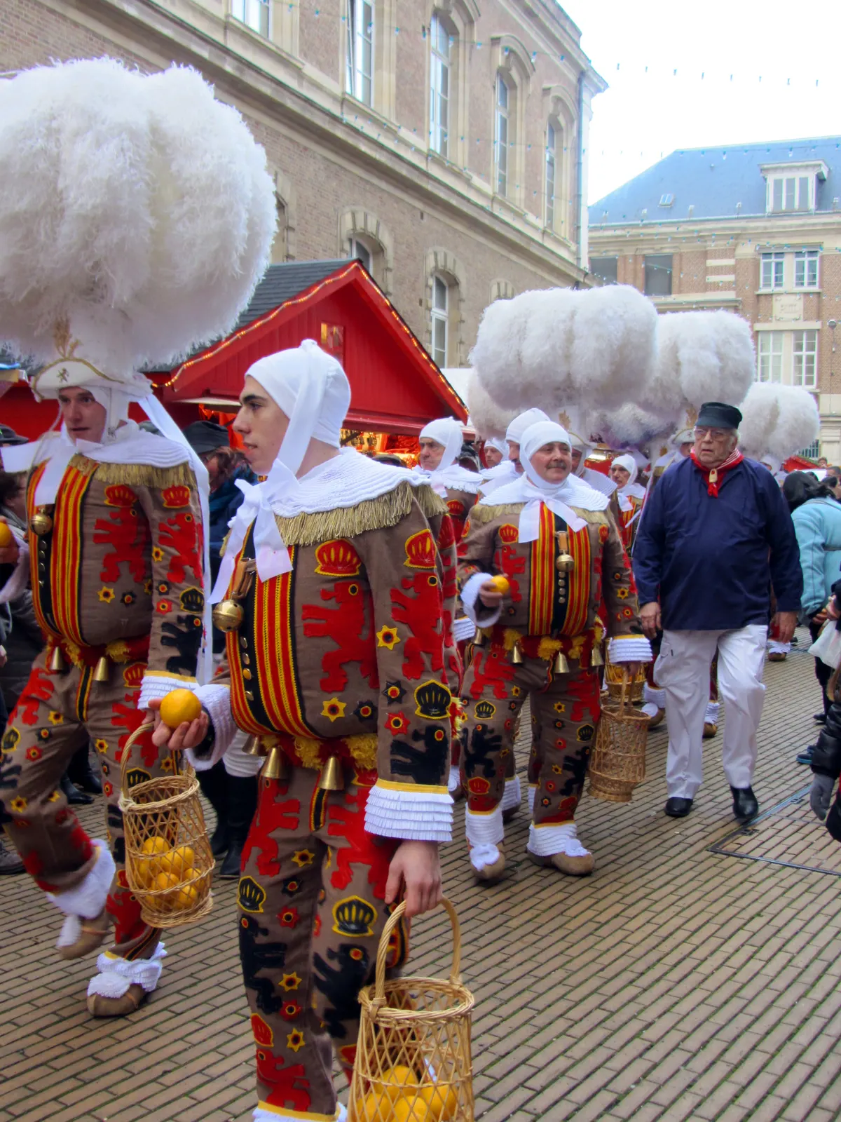 Gilles costumés devant un chalet du marché de Noël d'Amiens
