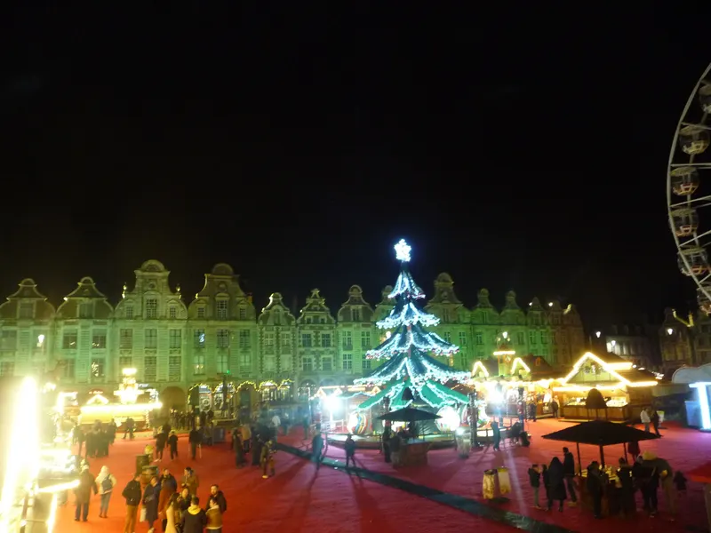 Manège et façades flamandes illuminées lors du marché de Noël d'Arras