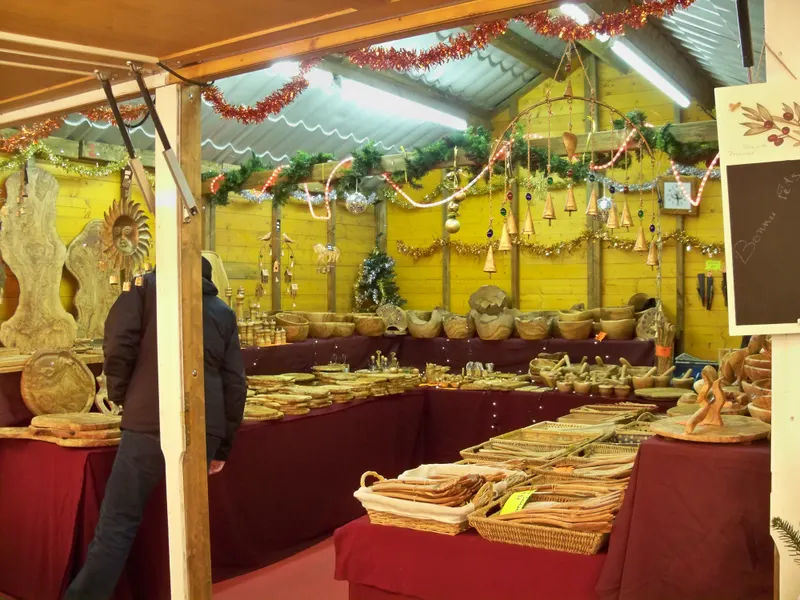 Étal d'artisanat en bois décoré de guirlandes au marché de Noël d'Avignon