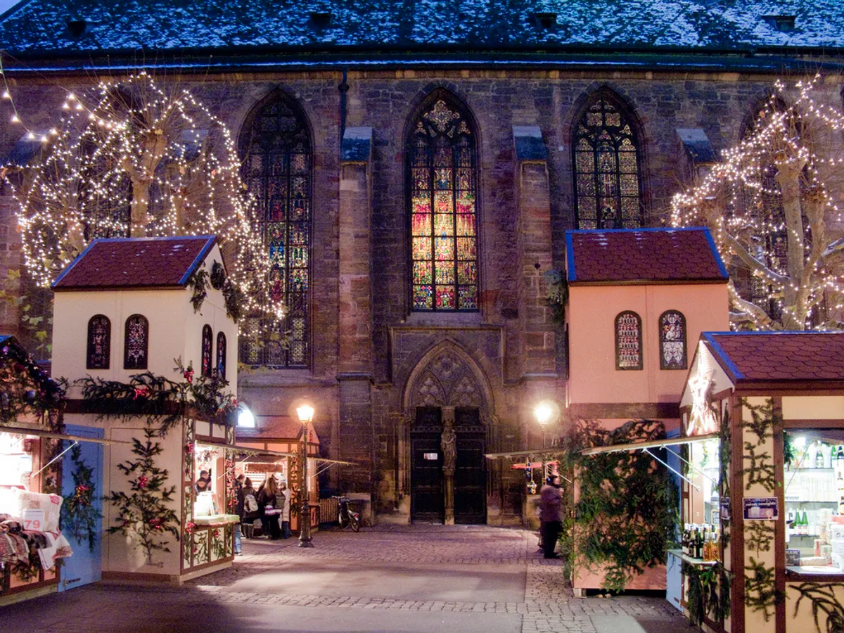 Chalets en bois et lumières devant l'église de Colmar au marché de Noël