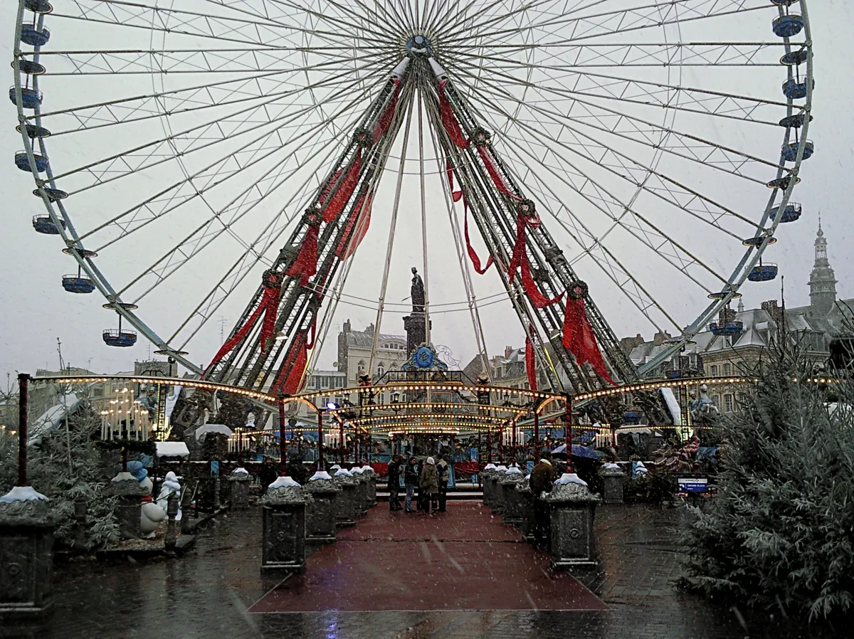 Chalets du marché de Noël de Lille sous le soleil, avec la grande roue en fond
