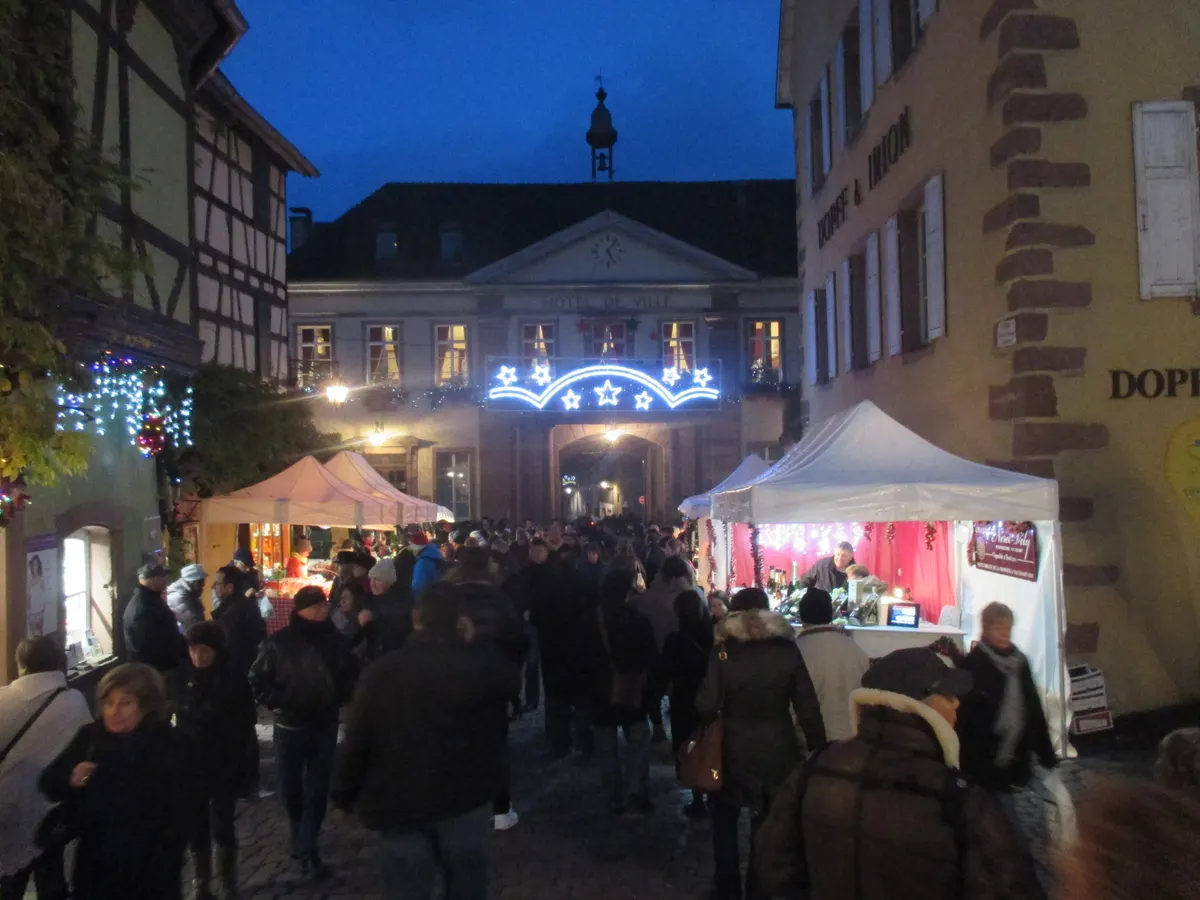 Foule et tentes du marché de Noël de Riquewihr au crépuscule